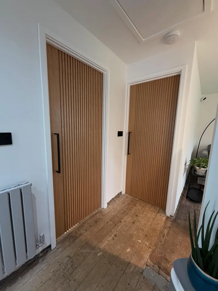 Reeded oak doors with black bar handles in a period hallway