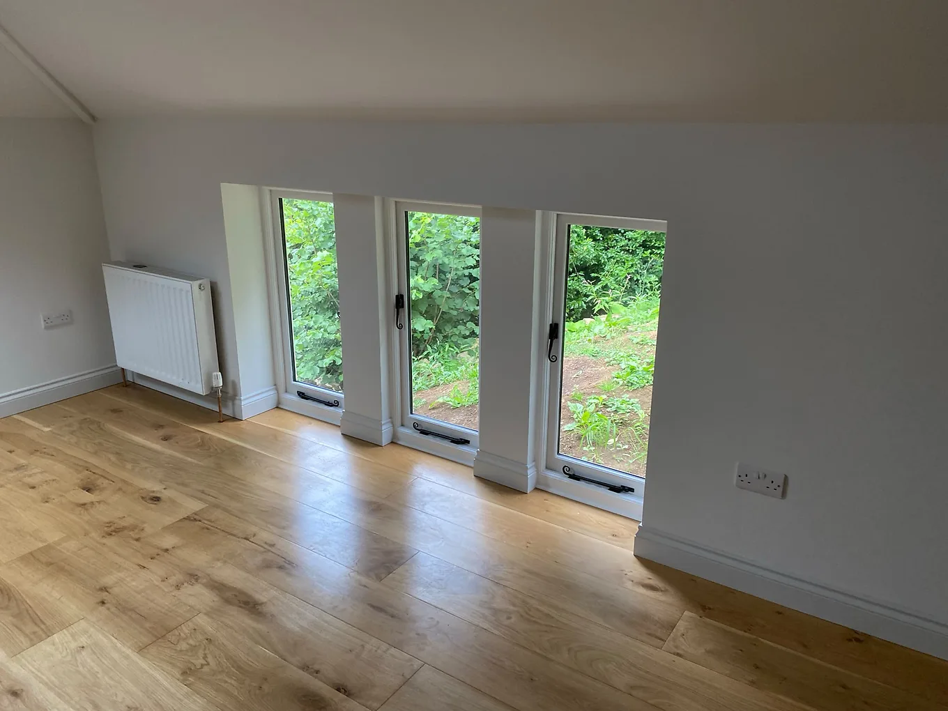 Finished engineered oak flooring with white skirting boards in a bright room