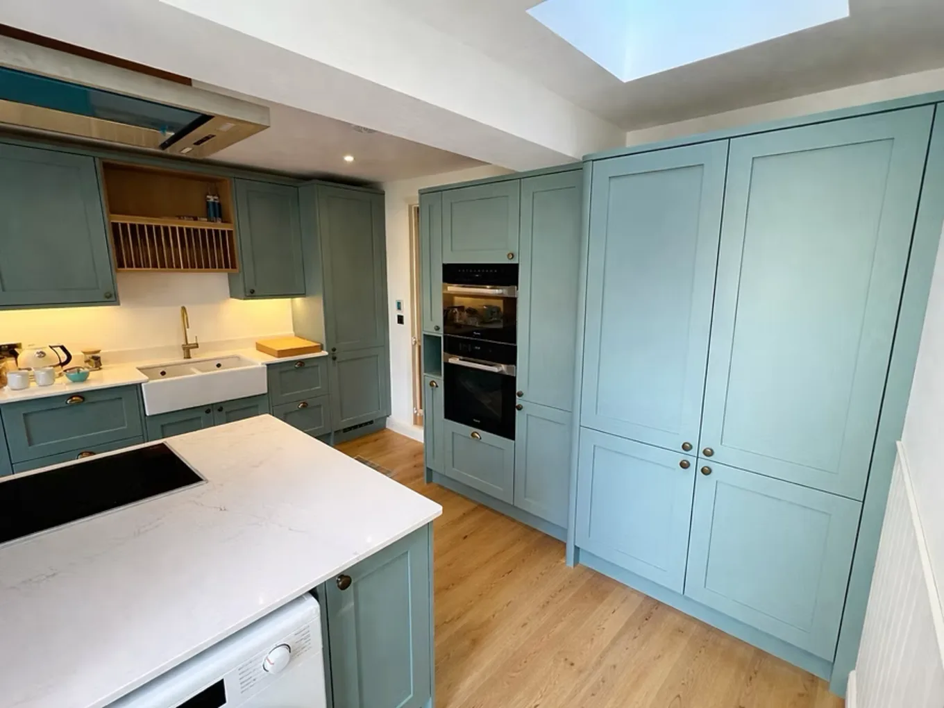 Bespoke sage-green shaker kitchen with brass hardware