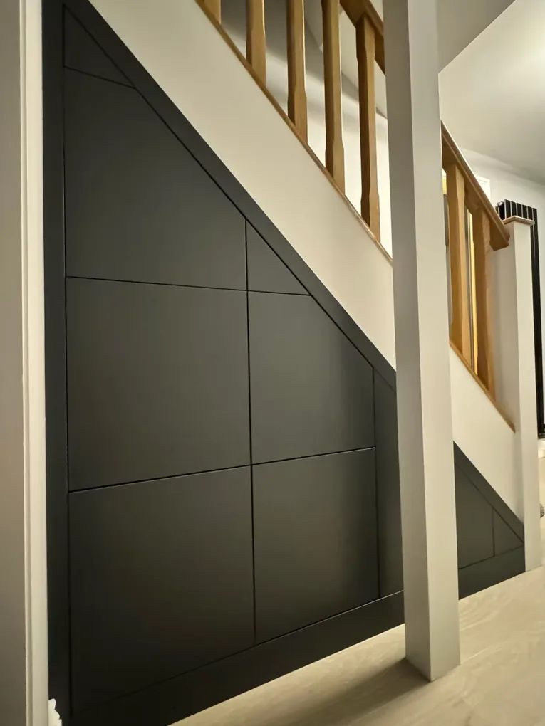 Bespoke under-stair storage cupboard in dark charcoal panelling